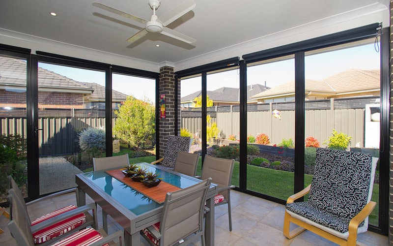 Enclosed alfresco dining room with ceiling fan and garden views